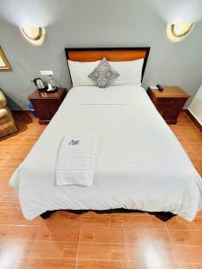 伊瓦拉Quinta San Carlos Hostel的一间卧室配有一张带2个床头柜的大型白色床