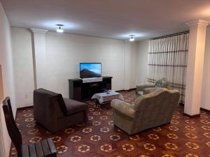 拉巴斯Departamentos a su altura en La Paz的客厅配有2把椅子和平面电视