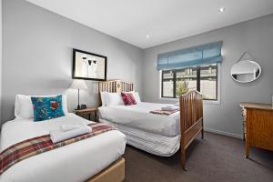 箭镇Elite Holiday Homes Queenstown - Arrowbrae的一间卧室设有两张床和窗户。