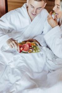 蒙特维尔蒙特维尔树梢海景酒店的一位有一盘食物的男女在床上
