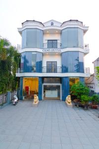 Trảng BàngGems Hotel - Khách sạn Trảng Bàng的一座蓝色的大建筑,前面有一个庭院