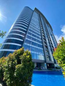达沃市AEON SUITES STAYCATION manage by ARIA HOTEL的一座高大的建筑,前面有一个游泳池