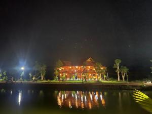Gia NghĩaDak Nguyen Homestay & Farm 2的一座在夜间水面上灯亮的大建筑