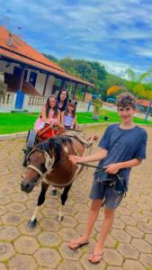 卡尚布Pousada temática Estrada Real的一个男孩站在一匹马旁边,有三个女孩