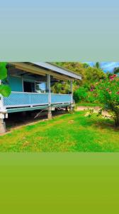 Te-Fare-AriiHaranai Camping & Tours的鲜花屋前的蓝色长椅
