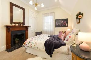 奥尔伯里Porters Cottage Classic的一间卧室配有一张床、一个壁炉和一个镜子