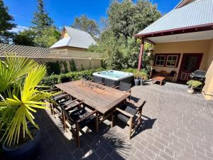 奥尔伯里Porters Cottage Oasis的一个带木桌和椅子的庭院和一个游泳池