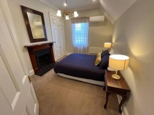奥尔伯里Porters Cottage Oasis的一间卧室配有一张床和一张带台灯的桌子