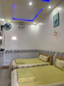 广义Nhà nghỉ Bá Thành - Lý Sơn的配有两张床铺的客房,墙上配有电视