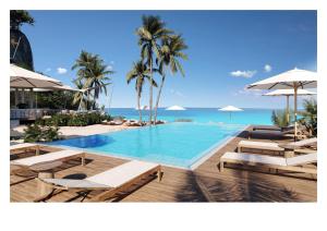 BambooSilversands Beach House Grenada的一个带椅子和遮阳伞的游泳池以及大海