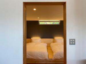 安昙野市北アルプス山麓の貸切サウナと貸別荘Azumino36stay的一间卧室配有两张位于镜子中的床