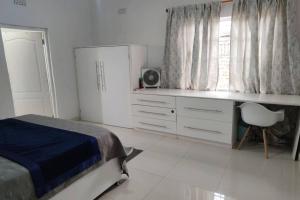 布兰太尔Nichi's Guesthouse - Cosy 3 bedroom with breakfast的一间卧室配有一张床、一张书桌和一个窗户。