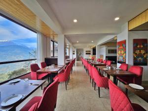 佩林Sumitel Pelling的餐厅设有桌子、红色椅子和大窗户