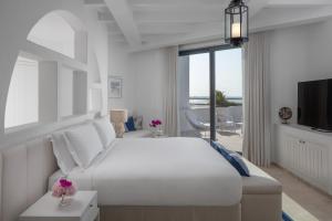 Al RahbaAnantara Santorini Abu Dhabi Retreat-Adults Only的白色卧室设有一张大床和电视。