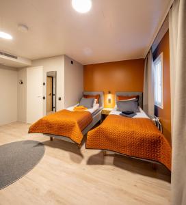 上维耶斯卡Hotelli Visiitti的橙色墙壁客房的两张床