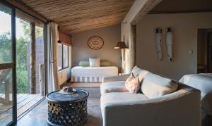 LentswelemoritiMashatu Lodge的客房设有两张床、一张沙发和一张桌子。