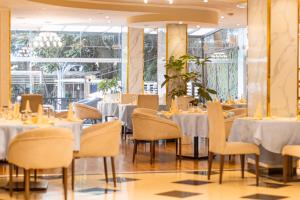 亚的斯亚贝巴Bonanza Addis Hotel的餐厅设有白色的桌椅和窗户。