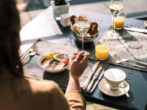 沃尔特湖畔韦尔登韦尔登富肯斯坦纳城堡酒店-世界顶级酒店集团的坐在桌子旁的女人,拿着一盘食物和酒杯