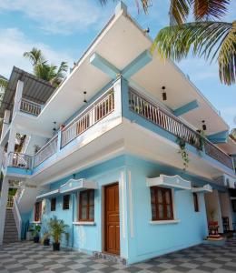 西奥利姆Whiteboard Homes Siolim的棕榈树的蓝色和白色房子