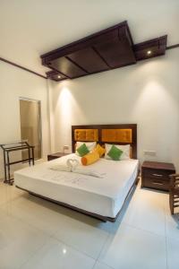 瓦都瓦Nirmala Hotel的卧室配有白色大床和黄色及绿色枕头