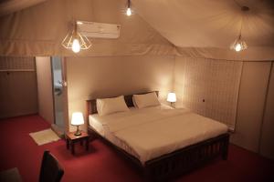 LakkidiAnamala Serenity Homestay Kerala的一个带两盏灯的帐篷内一间卧室,配有一张床