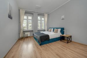 弗罗茨瓦夫Spacious 3-Bedroom Apartment Plac Grunwaldzki Wrocław by Renters的一间卧室配有一张带蓝色毯子的床和两个窗户。