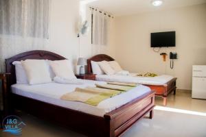 海地角J&G Villa Hotel的一间卧室配有两张床和一台平面电视