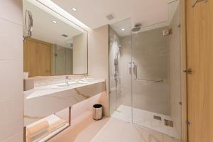 莎阿南Glenmarie Hotel and Golf Resort的一间带玻璃淋浴和水槽的浴室