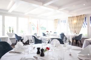施泰因海姆格鲁伯酒店的一间设有白色桌椅和窗户的用餐室