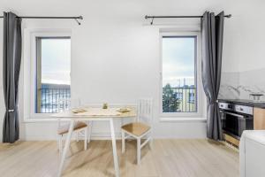 布拉格Apartment in Prague N1的白色的厨房配有桌子和2扇窗户