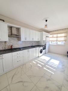特拉布宗kayan apart的厨房配有白色橱柜和瓷砖地板。