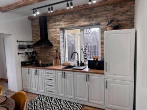 Nizhniy StudenyyFRIENDS HOUSE - Ізки 33的厨房配有白色橱柜和砖墙