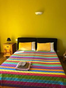 Serralunga di CreaCa' Cuore in Monferrato的一张带五颜六色毯子和帽子的床