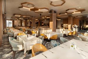 帕维尔巴尼亚Atmosphere Balneo Hotel & SPA的一间设有白色桌椅的餐厅