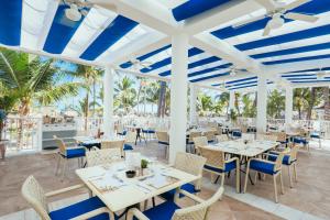 蓬塔卡纳Bahia Principe Fantasia Punta Cana - All Inclusive的餐厅拥有白色的桌椅和棕榈树
