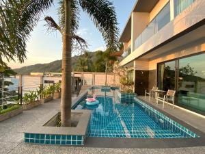 卡塔海滩Twin Villas Seaview Kata的一座棕榈树和房子的游泳池