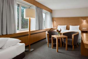诺德克豪特诺德韦克列文霍斯特会议中心NH酒店的酒店客房带两张床和一张桌子以及椅子。