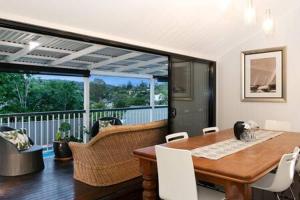 布里斯班The Indooroopilly Queenslander - 4 Bedroom Family Home - Private Pool - Wifi - Netflix的一间带桌子的用餐室和一个阳台