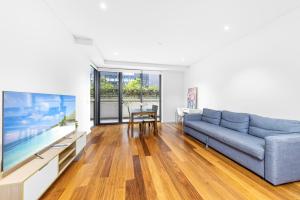 悉尼Super comfy 2B Apt in Burwood的客厅配有蓝色的沙发和大电视。