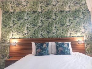 斯劳Langley Guest House的卧室内的一张带两个枕头的床,配有壁纸