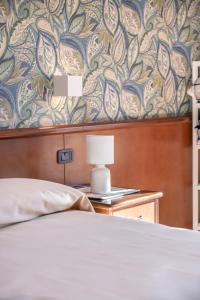罗卡拉索Hotel Rasinus的一间卧室配有一张床,墙上装饰着花卉图案的壁纸