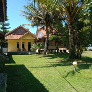 比哈尔Karang Besi Losmen的院子里棕榈树的黄色房子