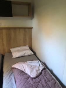比斯卡罗斯Mobil home détente Biscarrosse的小房间的小床,带枕头
