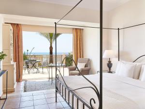 卢特拉基利尼斯Grecotel Olympia Oasis & Aqua Park的一间卧室配有一张床,享有海景