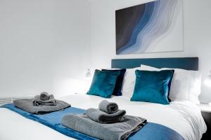 伯肯黑德Stylish 2 bedroom flat - 15 minutes to Liverpool City Centre的一间卧室,床上配有毛巾和蓝色枕头