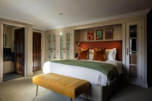 里克曼斯沃斯贝德福德阿姆斯酒店的一间大卧室,配有一张大床和一张长凳