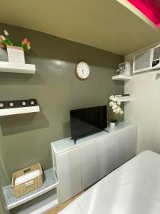 大雅台NA Suites at Pine Suites Tagaytay的客厅配有电视和墙上的时钟