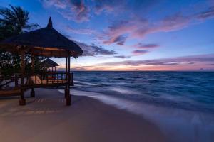 马累Banyan Tree Vabbinfaru的日落时分带凉亭和大海的海滩