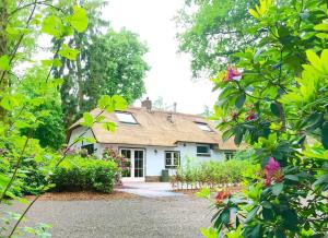 奥特罗Familiehuis De Erica - 12 p的前面有树木和鲜花的白色房子