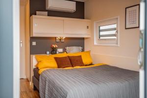KlittenHausboot Skyline的一间卧室配有一张带黄色枕头的床和一扇窗户